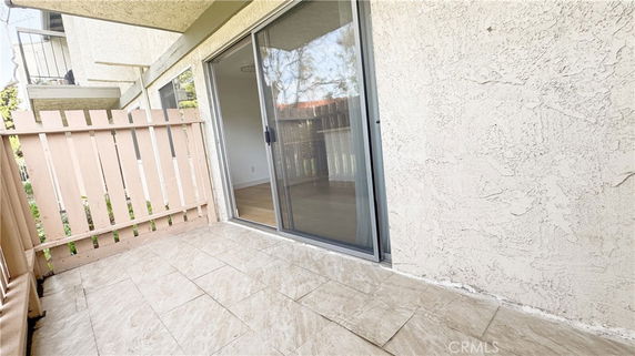 Outdoor patio area with sliding glass door and tiled flooring.