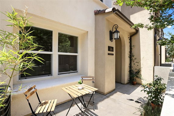 Front view of a house with a small outdoor seating area and two windows.