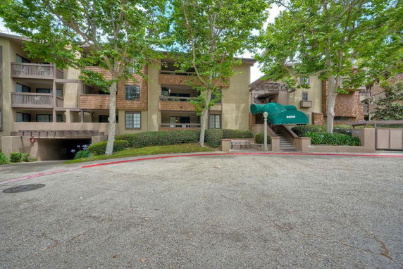 Front view of a multi-story residential building with balconies and stairs.