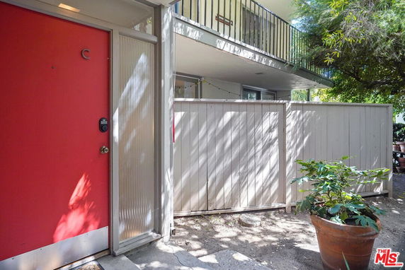 Front view of a building entrance with a red door and a balcony above.