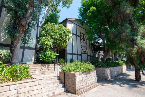 Front view of a building with trees and plants in the surroundings.
