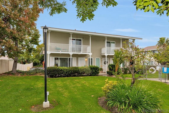 Front view of a two-story house with balconies and a front yard.