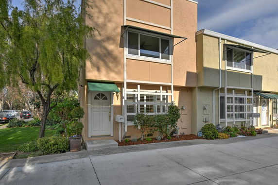 Front view of a multi-story residential building with large windows and a green awning above the door.