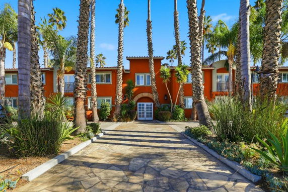 Front view of a two-story building with palm trees lining the entrance.