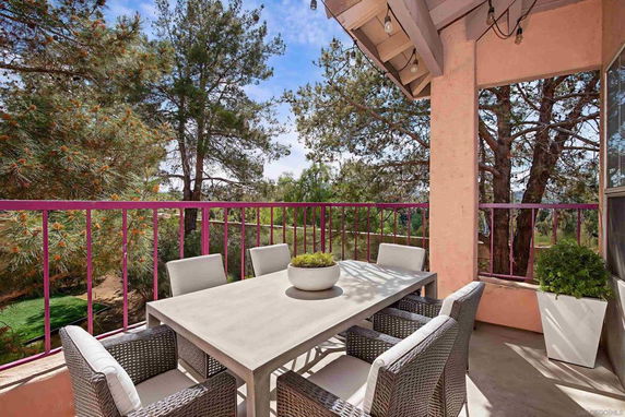 Outdoor patio with a dining table and chairs, surrounded by trees.
