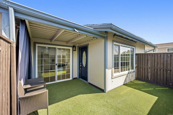 Front view of a house with a covered patio and sliding glass door.