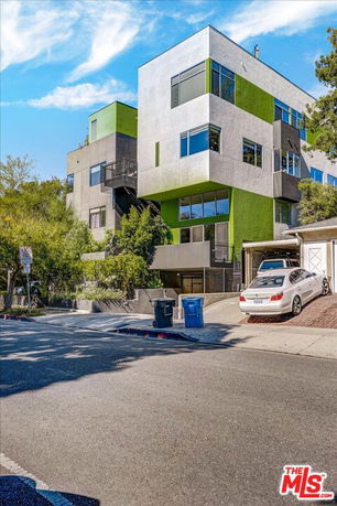 Front view of a modern multi-story building with green and gray exterior accents.