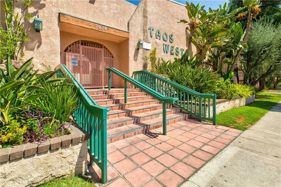 Front view of a building entrance with stairs and green railings.