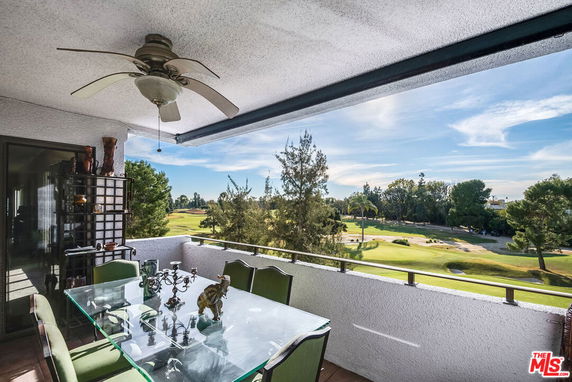 Balcony view overlooking a scenic landscape with trees and a golf course.