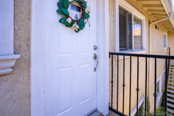 Entry view of a house with a white door and wreath, beige walls, and railings.
