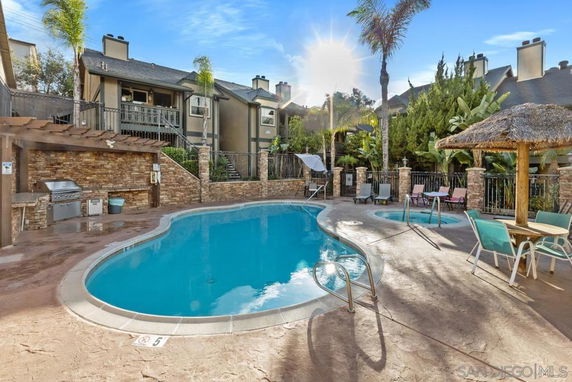 Outdoor swimming pool area with surrounding seating and barbecue grill.