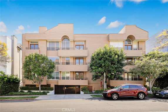 Front view of a multi-story building with balconies and a gated entrance.