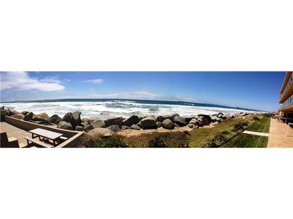 Panoramic view of the ocean with rocks and a pathway along the coast.