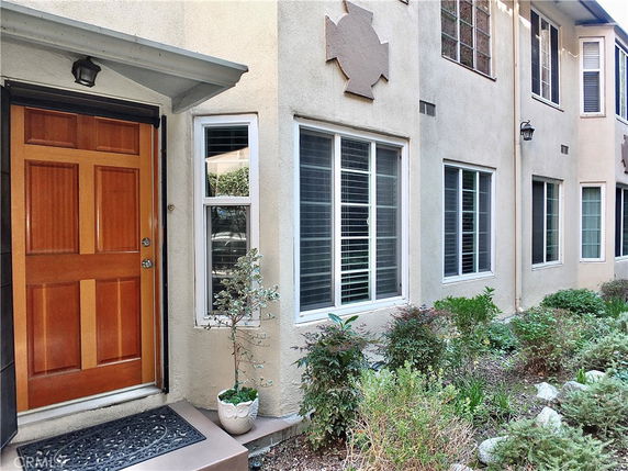 Front view of a house entrance with a wooden door and multiple windows.