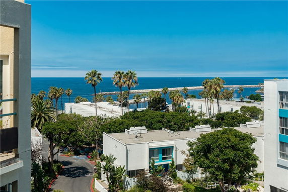 Panoramic view of coastal buildings with ocean and palm trees in the background.