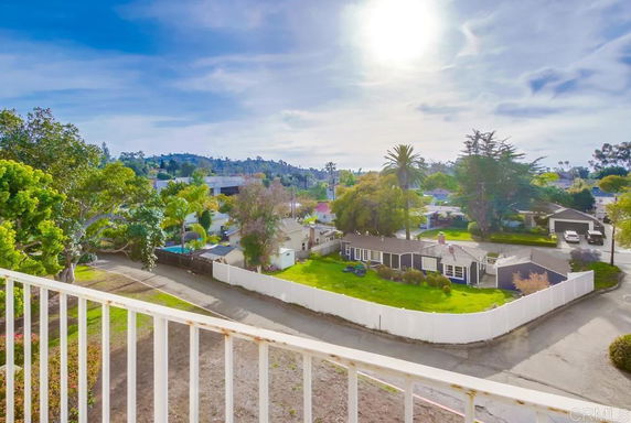 View of residential area from a balcony with trees and houses.