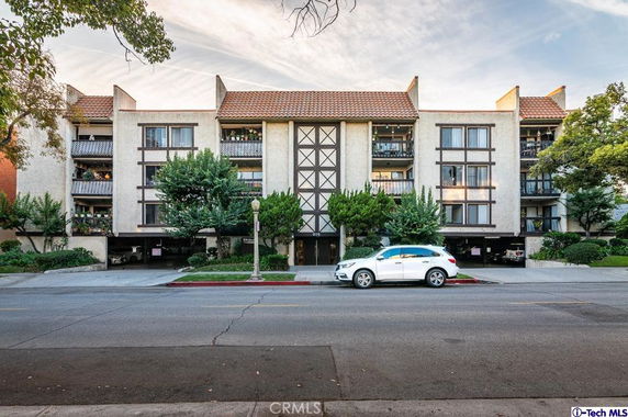 Front view of a multi-story residential building with balconies and a tiled roof.