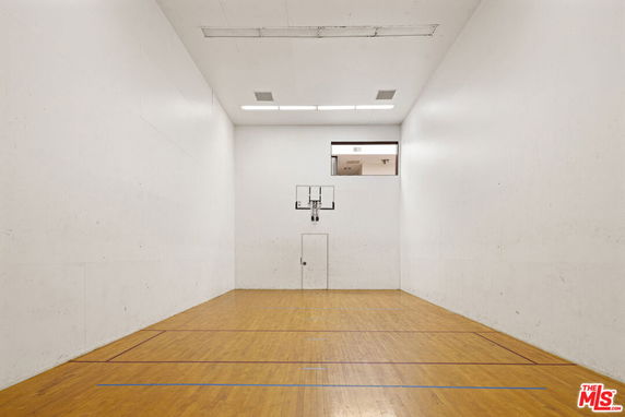 Indoor basketball court with wooden flooring and white walls.
