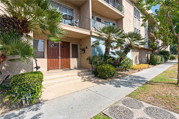 Front view of a multi-story residential building with balconies and a double-door entrance.