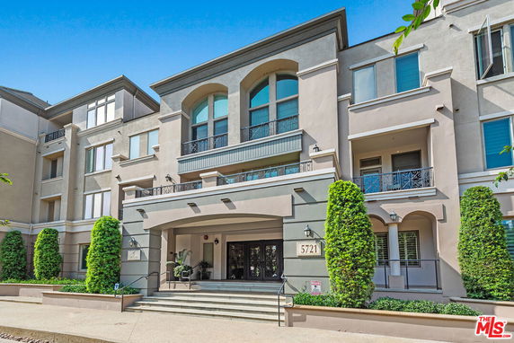 Front view of a multi-story residential building with balconies and entryway.