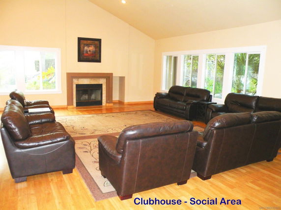 Interior view of a clubhouse social area with leather sofas and a fireplace.