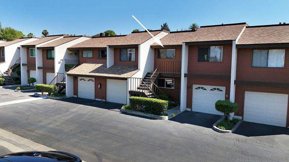 Front view of a row of two-story townhouses with garages and staircases leading to the upper floors.