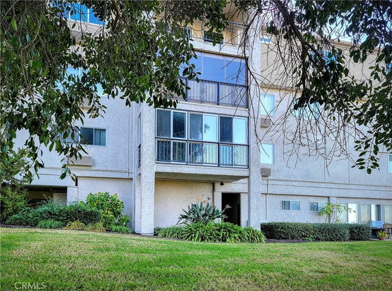 Front view of a multi-story residential building with balconies and large windows.