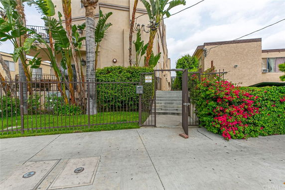 Front view of an apartment building with a gated entrance and stairs.