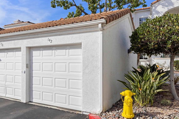 Front view of a two-car garage with white doors and a tile roof.