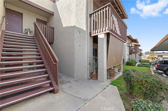 Side view of a multi-story apartment building with exterior stairs and balconies.