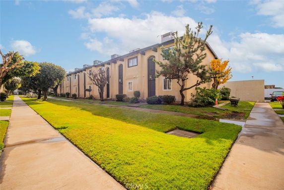 Front view of a multi-story residential building with a walkway and lawn.