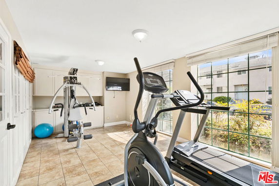 Gym area with exercise equipment and large windows in a house.