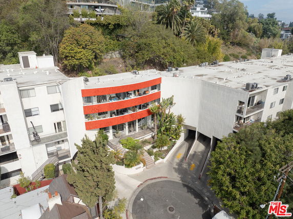 Front view of a multi-story apartment building with a curved facade and red accents.
