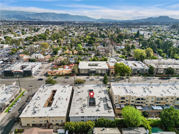 Aerial view of a residential area with multiple apartment buildings and a mountainous landscape in the distance.