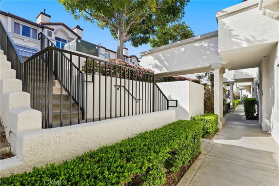 Front view of a multi-story residential building with stairs leading to an entrance.