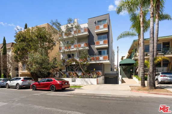 Front view of a multi-story apartment building with balconies and a modern facade.