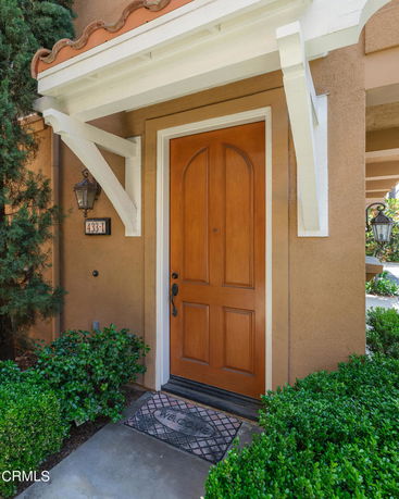 Front view of a house entrance with a wooden door and decorative arch above.