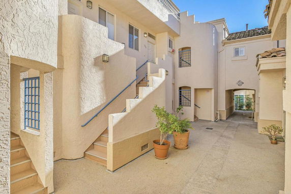 View of an apartment building with outdoor staircases and a courtyard.