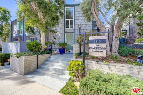 Front view of a townhouse with stairs leading to the entrance and a sign reading 'Doverwood Townhomes'.