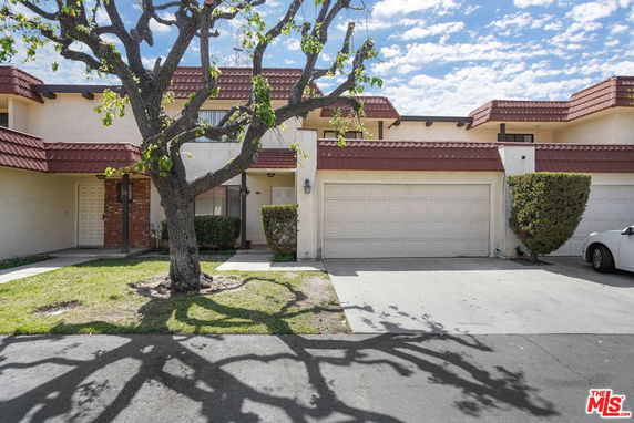 Front view of a two-story house with a double garage and a tree in front.