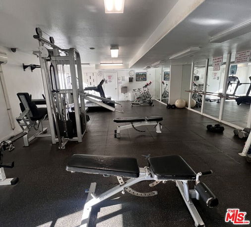 Indoor gym area with various exercise equipment and mirrors.
