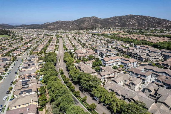 Panoramic view of a residential neighborhood with multiple houses and a central road.