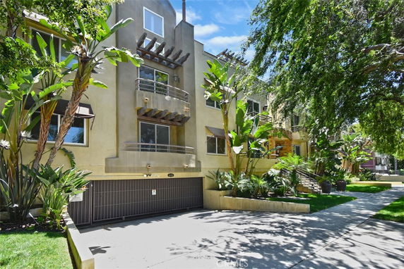 Front view of a multi-story residential building with balconies and a gated parking area.