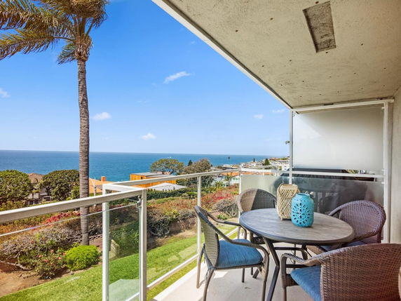 Balcony with a table and chairs overlooking the ocean.