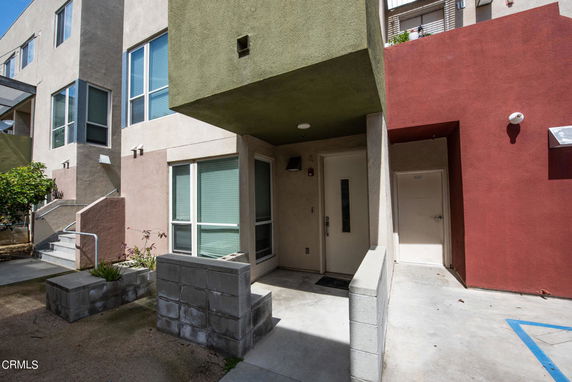 Front view of a modern multi-story building with different colored facade sections and a small entrance area.