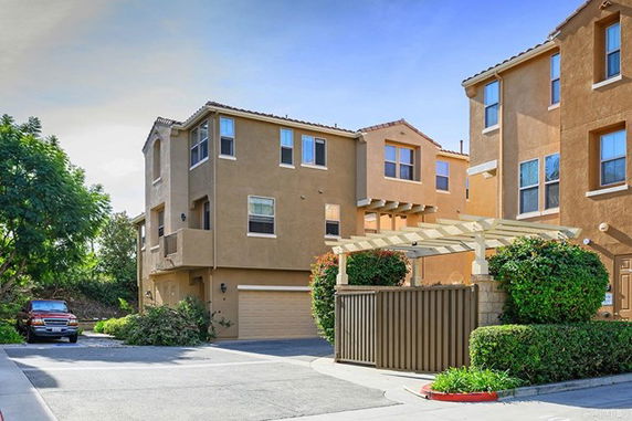 Front view of a multi-story house with a garage and a pergola structure.