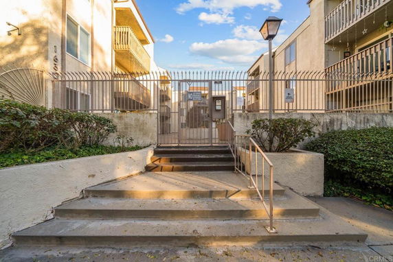 Front view of a gated residential building entrance with steps.