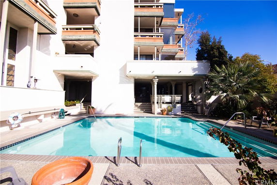 Outdoor swimming pool in front of a multi-story building.