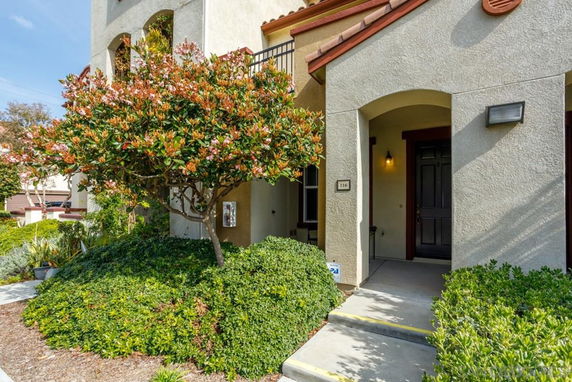 Front view of a house with an arched entryway and small garden.