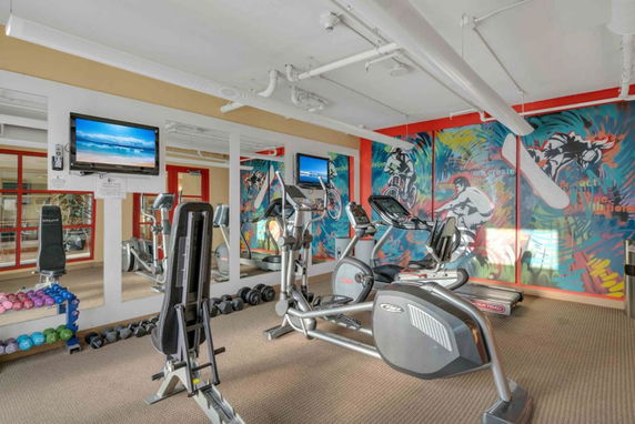 Indoor gym area with exercise equipment and vibrant wall murals.